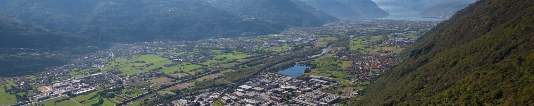 Vista aerea di Rogno (capoluogo) e del "laghetto" nel fondo della Valle Camonica, con vista che si estende sino al Lago d'Iseo